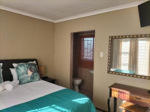 a bedroom with a bed and a mirror and a sink at AKANI Guesthouse Cosmo city in Roodepoort