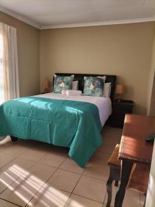 a bedroom with a large bed with a green comforter at AKANI Guesthouse Cosmo city in Roodepoort