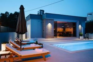 uma piscina com cadeiras e um guarda-sol e uma casa em Holiday Home TiA em Split