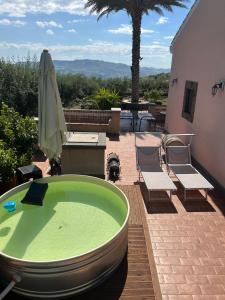 a green bath tub sitting on a patio with two chairs at la Tana di Luna in Adrano