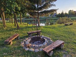 a fire pit with two benches and a swing at Domek letniskowy na Łowisku Muławki in Kętrzyn