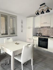 a white kitchen with a white table and chairs at la casetta di Sophia in Torrenova