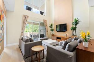 sala de estar con 2 sofás y TV en 3149 Magic Village 8 guests 4 suites 8min Disney, en Orlando