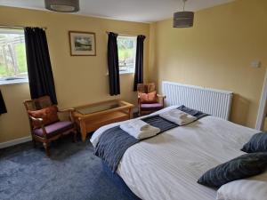 a bedroom with a large bed and two chairs at Ailean Chraggan in Aberfeldy