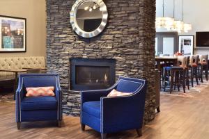 威斯康星德爾斯的住宿－Hampton Inn and Suites at Wisconsin Dells Lake Delton，两把蓝色椅子坐在壁炉前