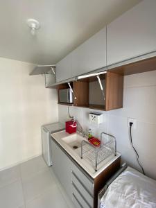 a kitchen with a sink and a red box on the counter at Aruana Azul 502 - Apto com AR, PISCINA, Varanda Integrada - Aluguel por Temporada in Aracaju