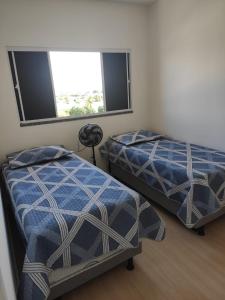 two beds in a room with two windows at Aruana Azul 502 in Aracaju