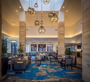 a lobby of a hotel with tables and chairs at Hilton Garden Inn Pittsburgh Airport in Moon Township