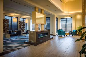 a lobby with a fireplace and chairs in a library at Hilton Garden Inn Pittsburgh Airport in Moon Township