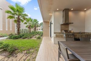 een patio met een tafel, een grill en palmbomen bij 7589 Magic Village 8 guests 4 suites BBQ near 192 Disney in Orlando