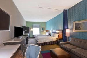 une chambre d'hôtel avec un lit et un canapé dans l'établissement Home2 Suites Pensacola I-10 At North Davis Hwy, à Pensacola