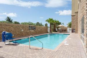 a swimming pool with a chair next to a building at Hampton Inn Fort Lauderdale Pompano Beach in Pompano Beach