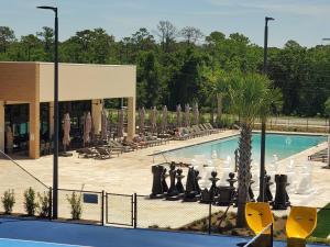 a pool with chairs and a palm tree in front of a building at 7462 Magic Village 8guests 4suites near Disney and 192 in Orlando