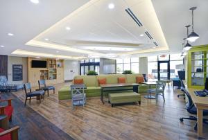 un vestíbulo de oficina con sofá, mesas y sillas en Home2 Suites By Hilton Dallas Desoto, en DeSoto