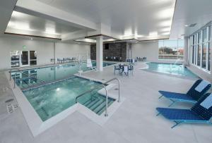 una piscina con sedie blu in un edificio di Hilton Garden Inn Wausau, WI a Wausau