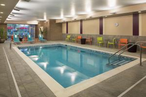 a swimming pool in a hotel room with colorful chairs at Home2 Suites By Hilton Mishawaka South Bend in Mishawaka