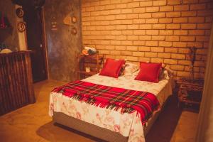 a bedroom with a bed with red pillows on it at Chalé 01 Itaipu Vale da Colina Niterói in Niterói