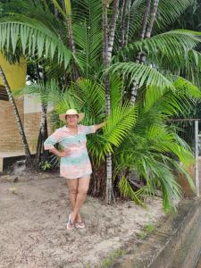 a woman in a hat standing next to a palm tree at Pousada Solar dos Lençóis in Barreirinhas