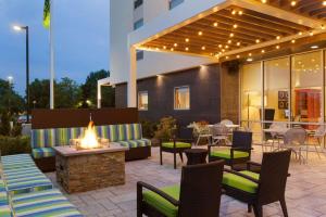 a patio with a fire pit and chairs and a building at Home2 Suites by Hilton Albany Airport/Wolf Rd in Albany