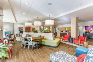 uma sala de estar com um sofá, mesas e cadeiras em Home2 Suites by Hilton Albany Airport/Wolf Rd em Albany