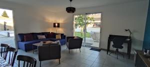 a living room with a blue couch and a table and chairs at 2 Maisons de 3 et 2 chambres avec grande piscine commune in La Teste-de-Buch