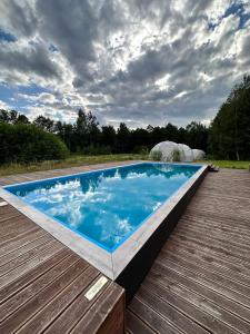 a swimming pool on a wooden deck with a cloudy sky at Glamping Stodoła Dome in Ściegny
