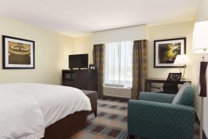 um quarto de hotel com uma cama e uma cadeira em Hampton Inn Fairmont em Fairmont