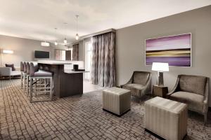 a living room with a bar and chairs and a kitchen at Embassy Suites by Hilton Charlotte Uptown in Charlotte