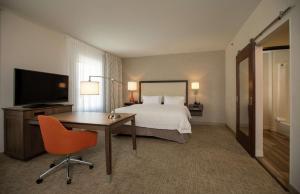 Habitación de hotel con cama, escritorio y TV. en Hampton Inn Mesa Verde/Cortez Co, en Cortez