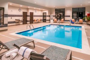 a large pool in a hotel with chairs and a table at Hampton Inn & Suites Wixom/Novi/Detroit, Mi in Wixom