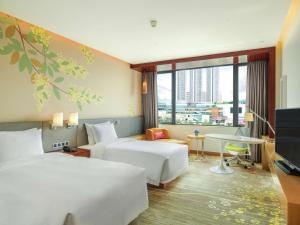 a hotel room with two beds and a tv at Hilton Garden Inn Foshan in Foshan