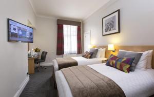 倫敦的住宿－Thistle London Bloomsbury Park，酒店客房设有两张床和一台平面电视。