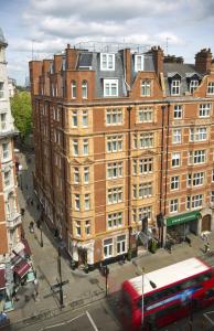 een rode bus die langs een groot bakstenen gebouw rijdt bij Thistle London Bloomsbury Park in Londen