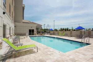 uma piscina num hotel com cadeiras e guarda-sóis em Hampton Inn and Suites Jacksonville/Orange Park, FL em Orange Park