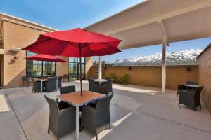 Hampton Inn & Suites Wells, Nv في ويلز: فناء مع طاولة مع مظلة حمراء