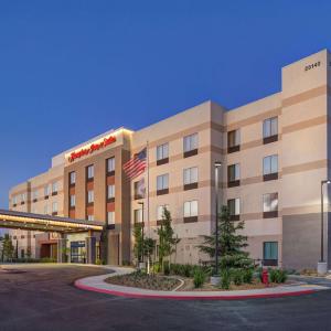 een hotelgebouw met een Amerikaanse vlag ervoor bij Hampton Inn & Suites Murrieta in Murrieta