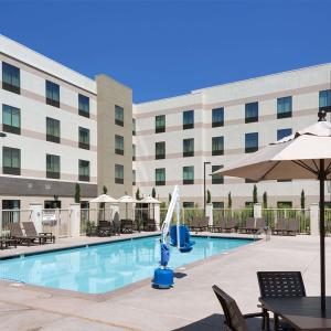 uma piscina em frente a um hotel com cadeiras e um guarda-sol em Hampton Inn & Suites Murrieta em Murrieta