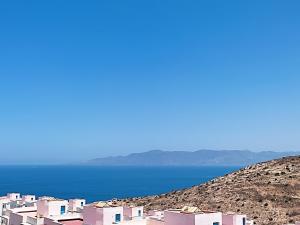 a group of pink houses on a hill next to the water at Peaceful Apartment in Al Hoceïma