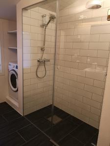 a shower in a bathroom with a washing machine at Cosy apartment on a quiet street in Kristiansand