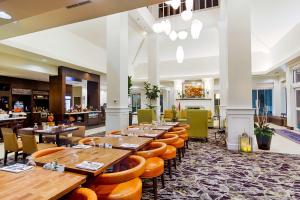 un restaurante con mesas de madera y sillas naranjas en Hilton Garden Inn Salina en Salina