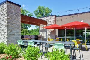 un patio con mesas, sillas y sombrillas rojas en Home2 Suites By Hilton Dayton Vandalia en Dayton