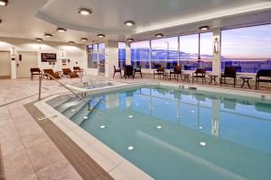 Hampton Inn & Suites by Hilton Grande Prairie في غراندي بريري: مسبح في الفندق مع الكراسي والطاولات