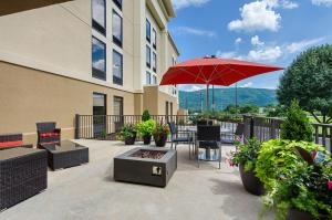 a patio with a red umbrella and a table and chairs at Hampton Inn Covington VA in Covington