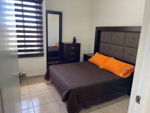 een slaapkamer met een bed met een oranje kussen en een spiegel bij Departamento para familias in Mazatlán