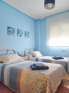 Casa Carla في Sotoserrano: سريرين في غرفة بجدران زرقاء