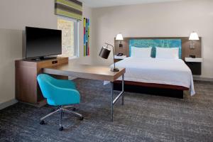 フラッグスタッフにあるHampton Inn Suites Flagstaff Eastのベッド、デスク、テレビが備わるホテルルームです。