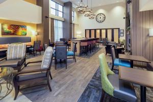 モーガンタウンにあるHampton Inn & Suites Morgantown / University Town Centreのテーブルと椅子、壁掛け時計のあるレストラン