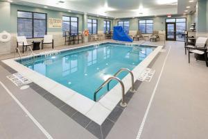 a large swimming pool in a building with tables and chairs at Hampton Inn & Suites Morgantown / University Town Centre in Morgantown
