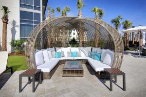 聖奧古斯丁海灘的住宿－Embassy Suites St Augustine Beach Oceanfront Resort，柳条秋千,配有白色靠垫和蓝色枕头