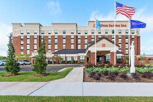 uma frente de hotel de um edifício com uma bandeira americana em Hilton Garden Inn Edmond/Oklahoma City North em Edmond